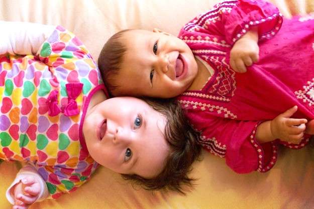 two happy babies wearing colorful clothes | When Do Babies Start Talking? Looking Forward To Key Milestones | when do babies talk