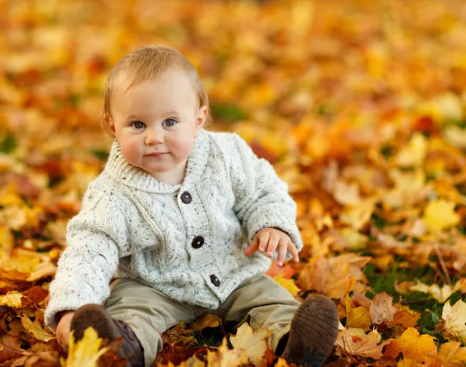 baby sitting in a pile of leaves