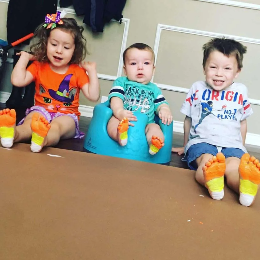 kids with feet painted in the color of candy corn
